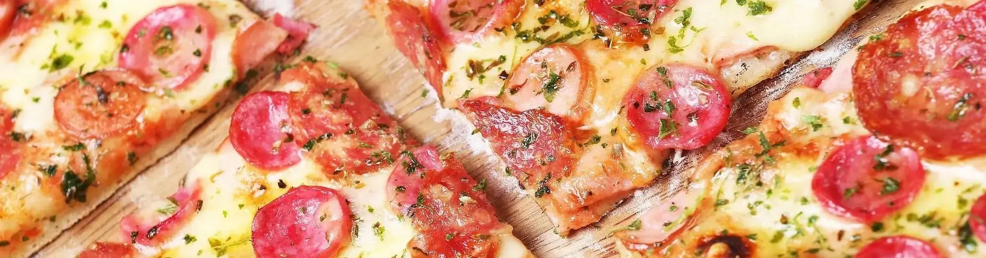 A Scrumptious Sausage Pizza slice in squares with chunk of big pepperonies and tomatoes