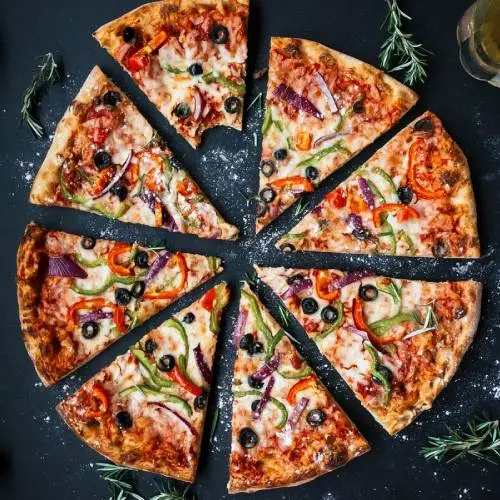 Scrumptious Sausage pizza in eight slices with rosemary garnish.