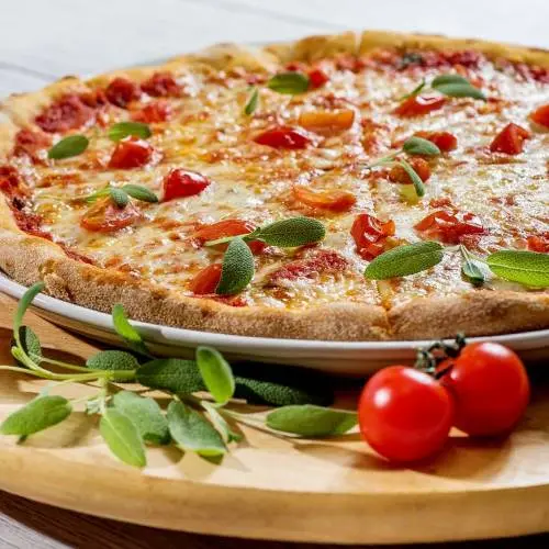 A slice of scrumptious sausage pizza with fresh herbs and tomatoes.